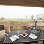 Patio with table, chairs, and view of fields and water.