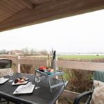 Holiday home with terrace, garden, and wooden railing. Windows with blinds and chimney.