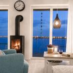 Wohnzimmer mit Kamin, Balkon und Blick auf Wasser.