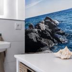 Badezimmer mit Meeresmotiv an der Wand, Waschbecken und Schale auf Schrank