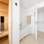 Sauna mit Holzbank und Dusche mit Badewanne