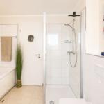 Bad mit Dusche, Badewanne und Spiegelschrank. Wandbild Leuchtturm.