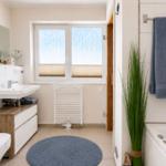Badezimmer mit Badewanne, Waschbecken und Fenster mit Blick.