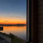 Aus dem Fenster blickt man auf einen See bei Sonnenuntergang mit gegenüberliegenden Häusern.