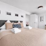 Schlafzimmer mit Bett, Nachttisch, Schreibtisch und Wandbildern.