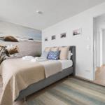Schlafzimmer mit Bett, Wandbild und Blick aufs Meer