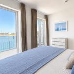 Schlafzimmer mit Blick auf Hafen und Wasser, großes Bett, Fenster und Tür zum Balkon.