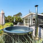 Haus mit Terrasse, Liegen, Whirlpool und rotem Hängemattenbereich.