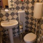 Badezimmer mit Waschbecken, Toilette und Spiegel an schwarz-weiß gemasertem Wandverkleidung.
