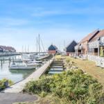 Harbor with sailboat, parking spots, and view of the sea.
