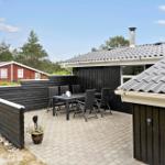 Black house with terrace and garden. Surrounded by trees and grass.