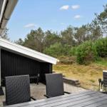 Terrace with table, chairs, and umbrella. Background: wooden house and white fence.