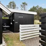 Black house with terrace, table, chairs, and umbrella.