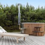 High-quality wooden hot tub on terrace with shower fixture and chimney in background.