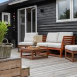 Deck with wooden furniture, seating group, and table. Dark wood wall in background.