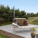 Terrace with table, chairs, umbrella, and grill. View of grassland and trees.