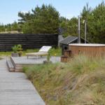 Terrace with table, chairs, and umbrella. Natural path through dune landscape.