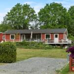 Red house with terrace, grill, and greenhouse in the garden.