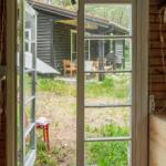 Wood-paneled accommodation with bed, sofa, table and chairs, window, and ceiling lights.
