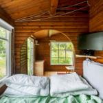 Living space with wooden walls, sofa, table, and window with view of green.