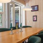 Living and dining area with wood paneling, dining table, chairs, and wood stove.