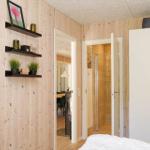 Washing machine in small room with mirror cabinet and green cushion seat.