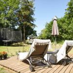 Wooden table with chairs and drinks in front of stacked firewood and trees.