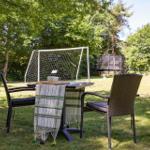 Backyard with lounge chair, umbrella, and hanging chair in front of a house.