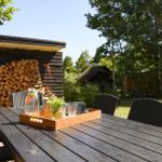 Deck with seating group and wooden planks. Background: green lawn and trees.
