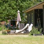 Deck with dining table and chairs in front of a house with dark wood siding.