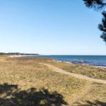 Beach with gravel shore and blue sea under clear sky