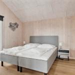 Bedroom with wooden walls, bed, and window to the forest.