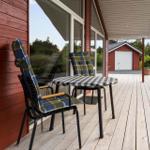 Two lounge chairs on a terrace in front of a wooden house with a view of the forest.